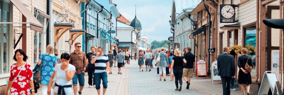 Ihmisiä kävelemässä Vanhan Rauman Kuninkaankadulla värikkäiden puutalojen reunustamalla kävelykadulla kesäpäivänä.